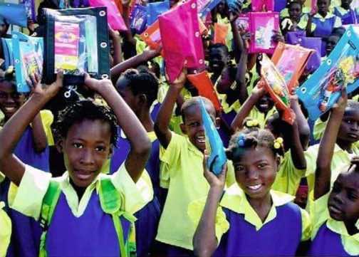 Children holding up school supplies purchased by W. C. Hunter as part of “Haiti Feed the Children”